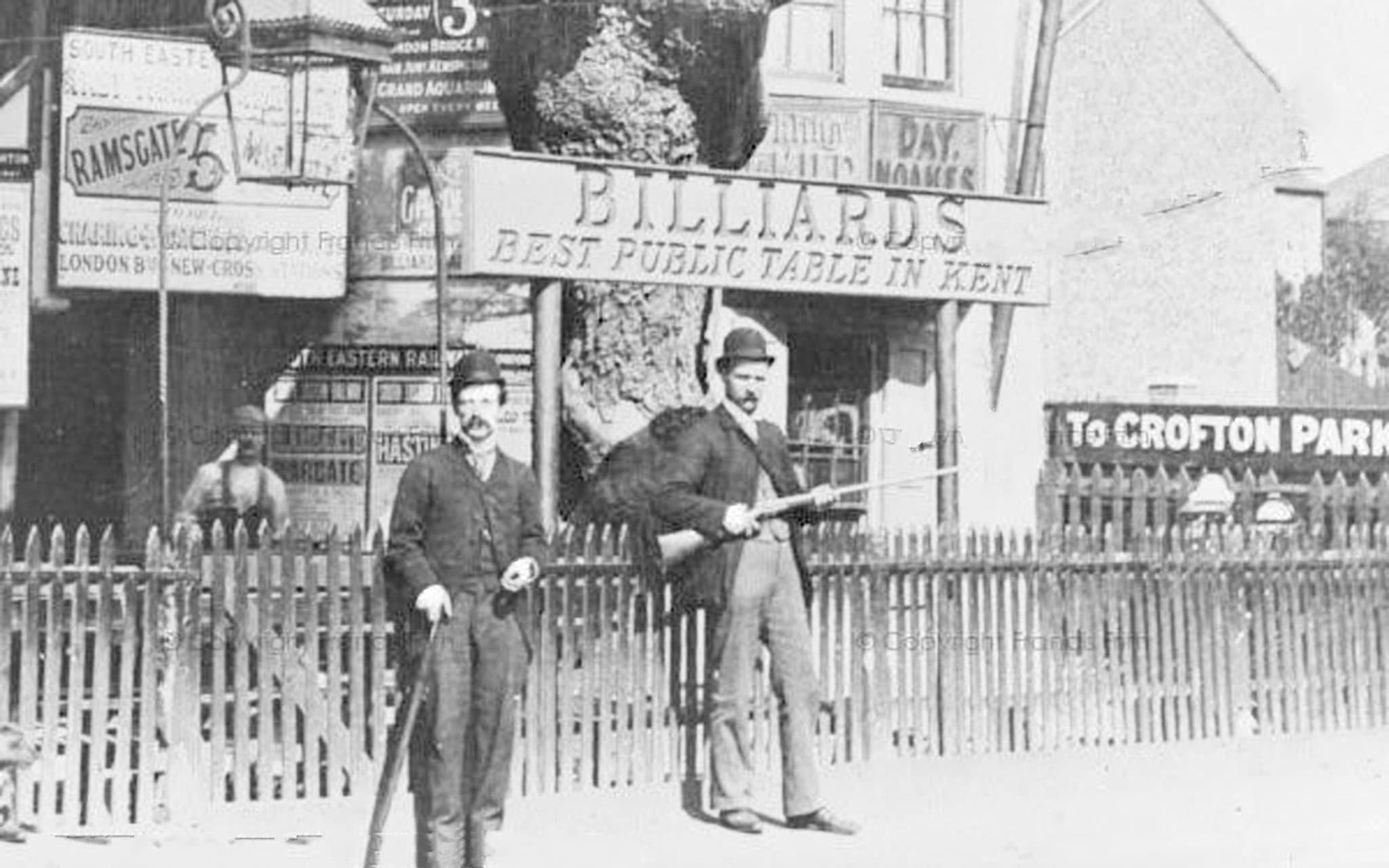 Two men holding shotguns outside the Brockley Jack billiards house around 1880