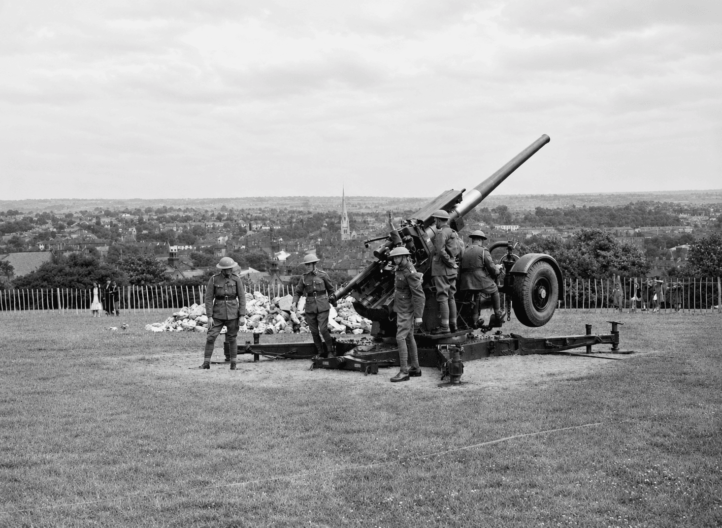 A 4.7-inch anti-aircraft gun and its crew on Hilly Fields in 1942, with Brockley's rooftops and a church spire behind
